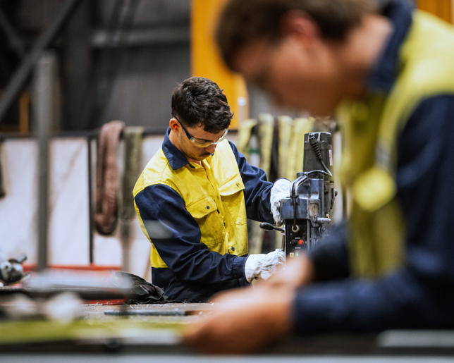 Large industrial warehouse with machinery and yellow support structures , with steel and metal processing equipment.