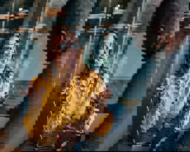 Businessman and businesswoman accountants sitting at a desk, discussing financial strategy using a laptop in the office.