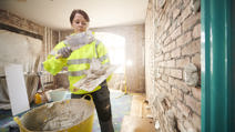 Female plasterer applying drywall adhesive