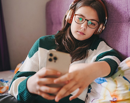 Young teen girl with headphones looking pensively at mobile