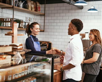 Volunteers organize and distribute items at a charity event, with one smiling individual holding a can.