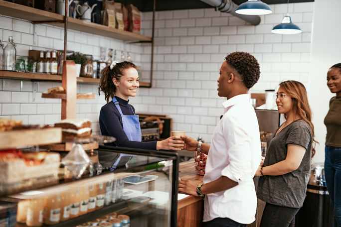 Volunteers organize and distribute items at a charity event, with one smiling individual holding a can.