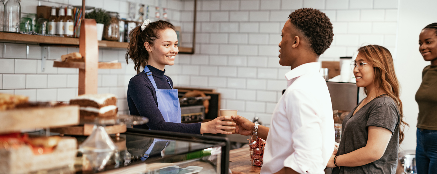Volunteers organize and distribute items at a charity event, with one smiling individual holding a can.