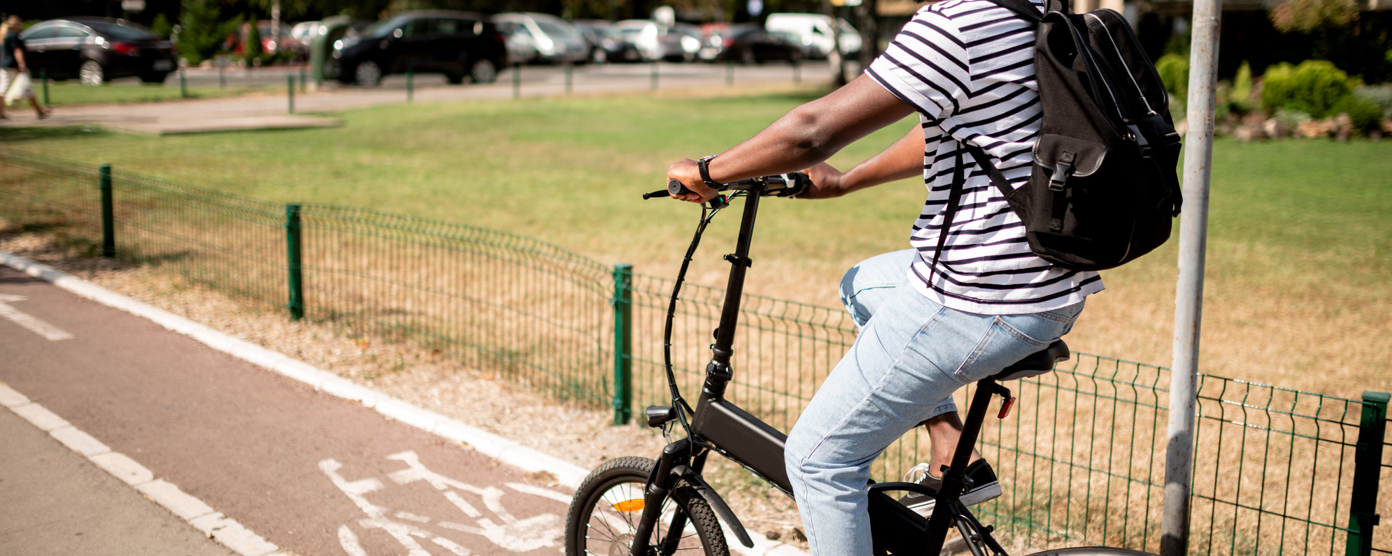 A young man is riding an electric bike on a dedicated bike path.
