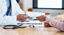 Doctor handing a sick note to a patient