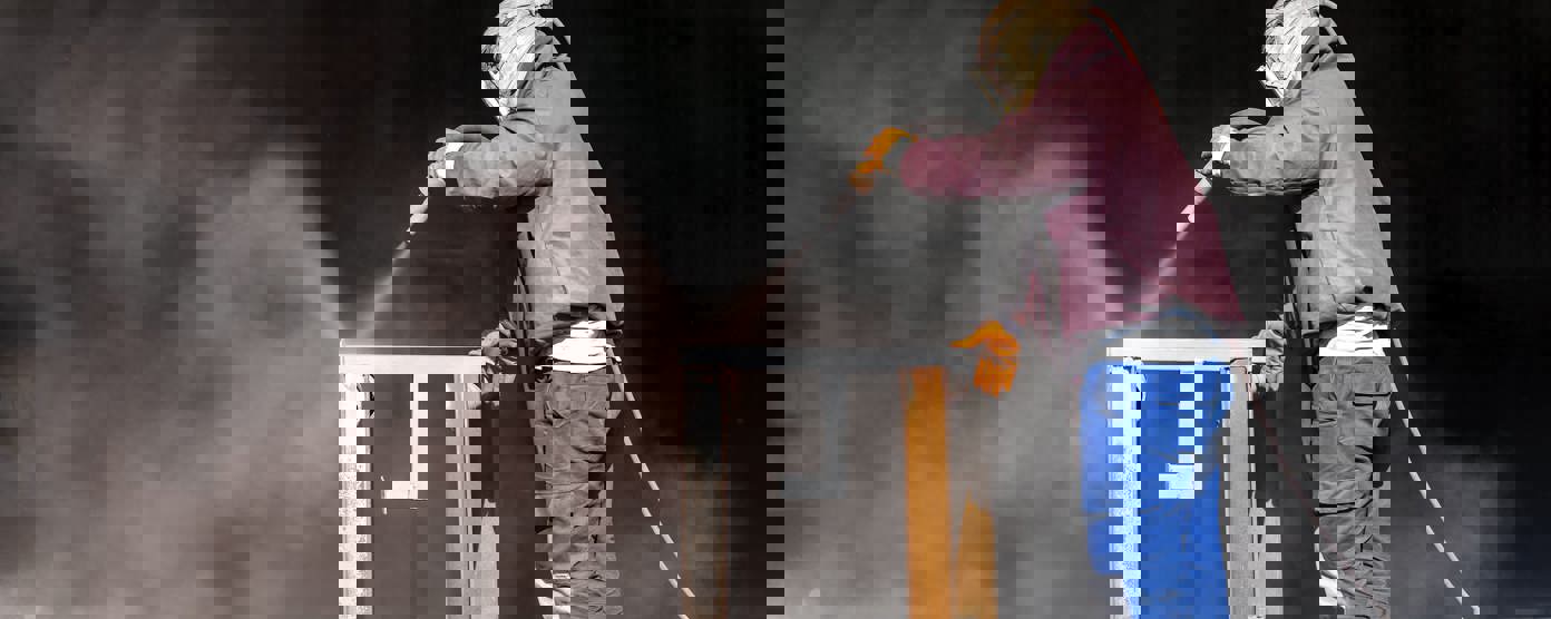 Sandblaster is sandblasting to steel material.